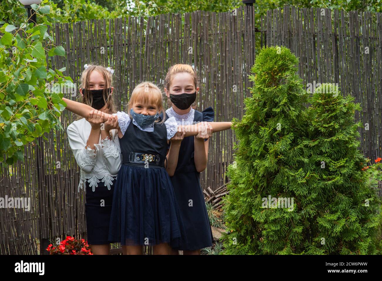 Three schoolgirls wearing masks and going back to school during covid ...