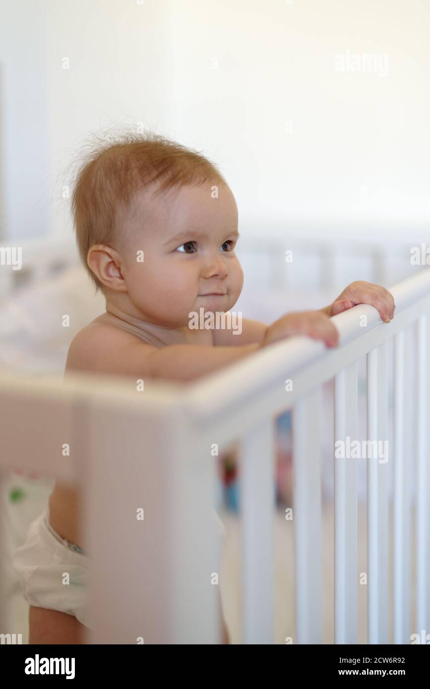 8 month old baby girl standing in the crib Stock Photo Alamy