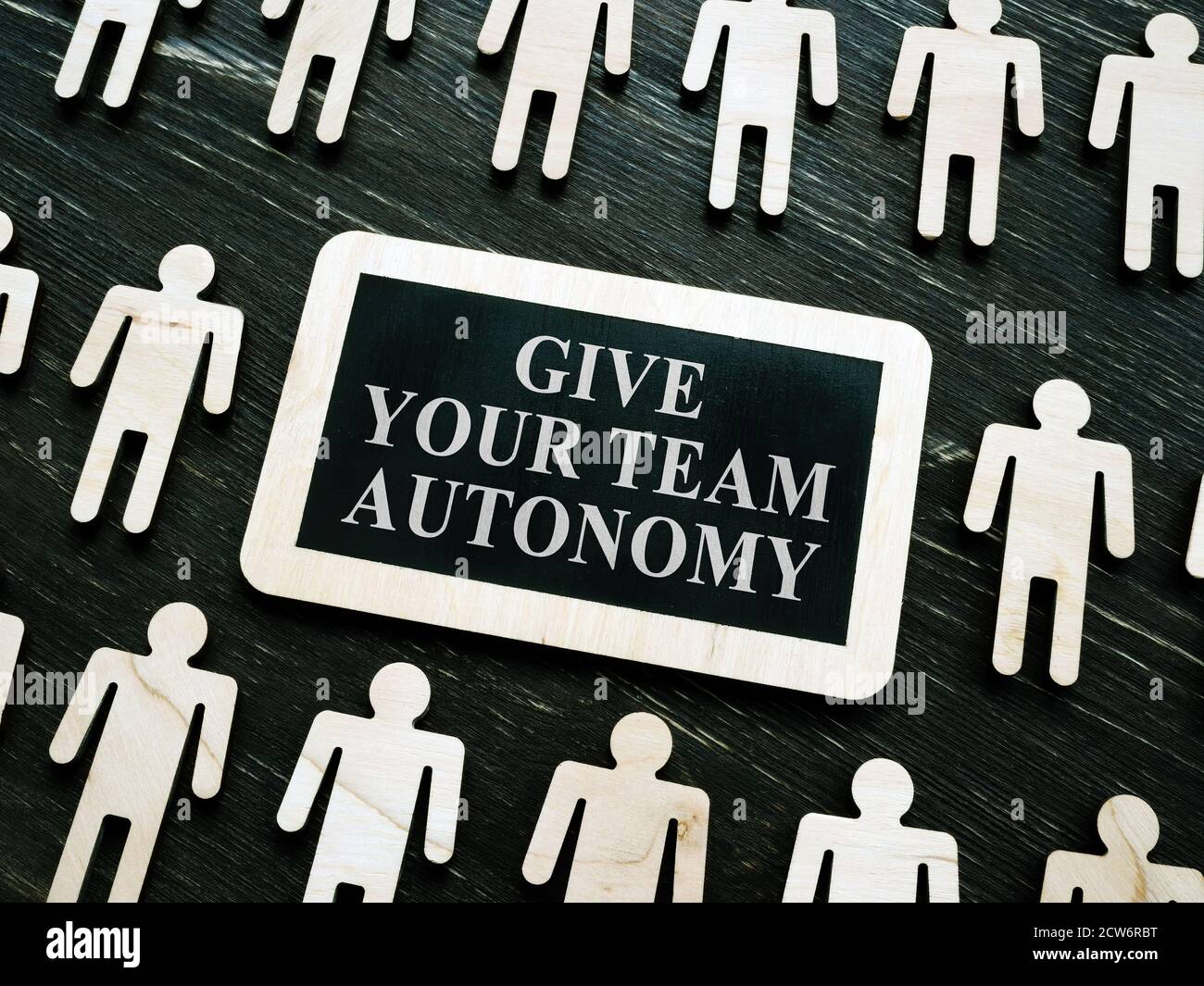 Giving your team autonomy quote and wooden figures. Stock Photo