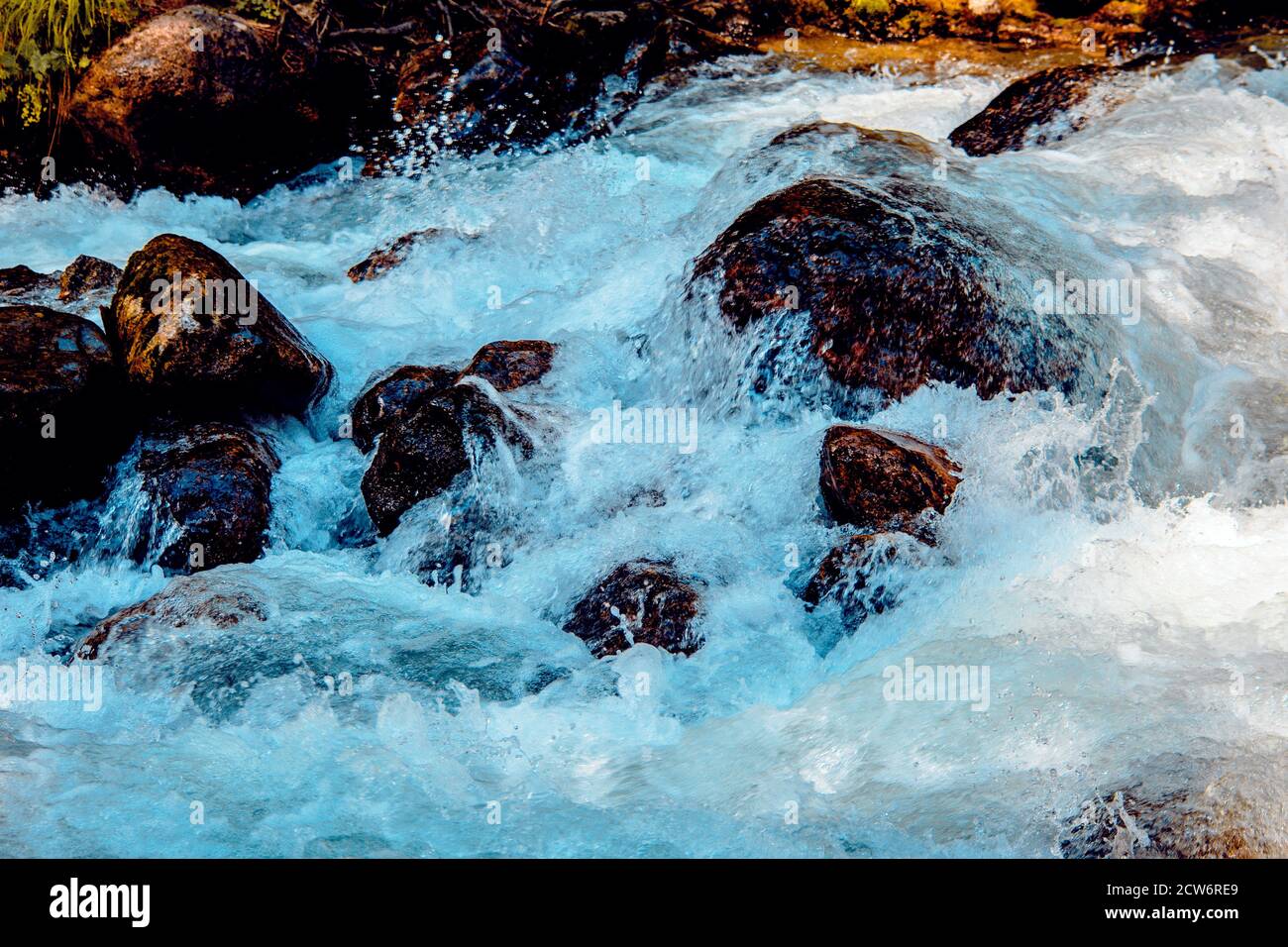 the water of a stormy mountain river flowing among stones and boulders ...