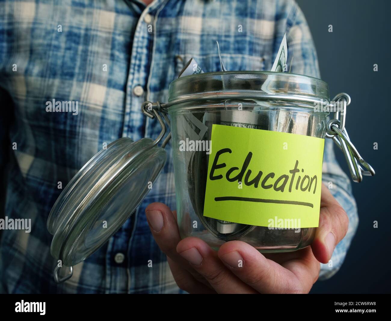 Jar with dollars and the inscription Education. The guy keeps his college savings. Stock Photo