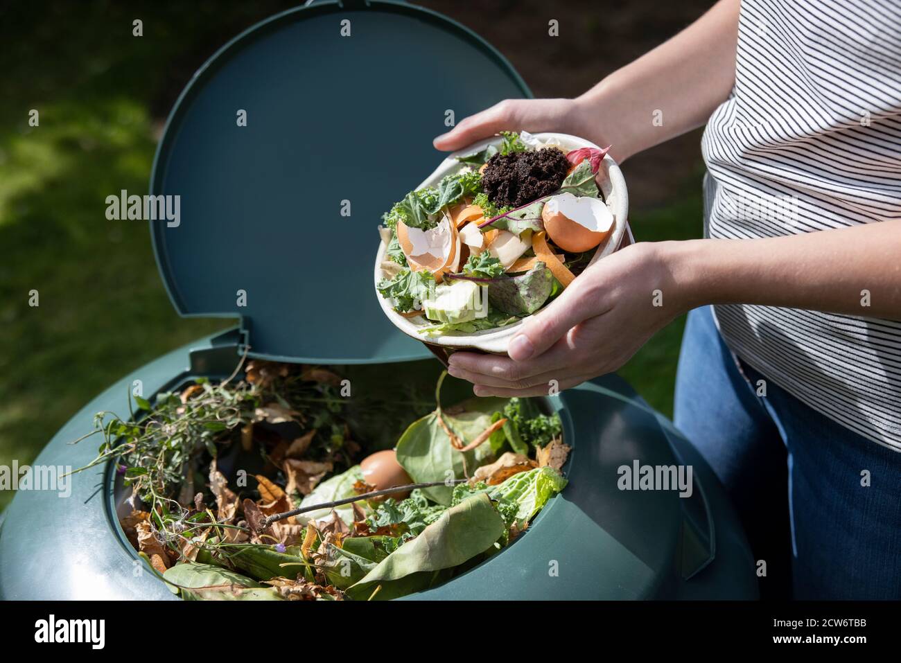 Close Up Of Woman Emptying Food Waste Into Garden Composter At Home Stock Photo