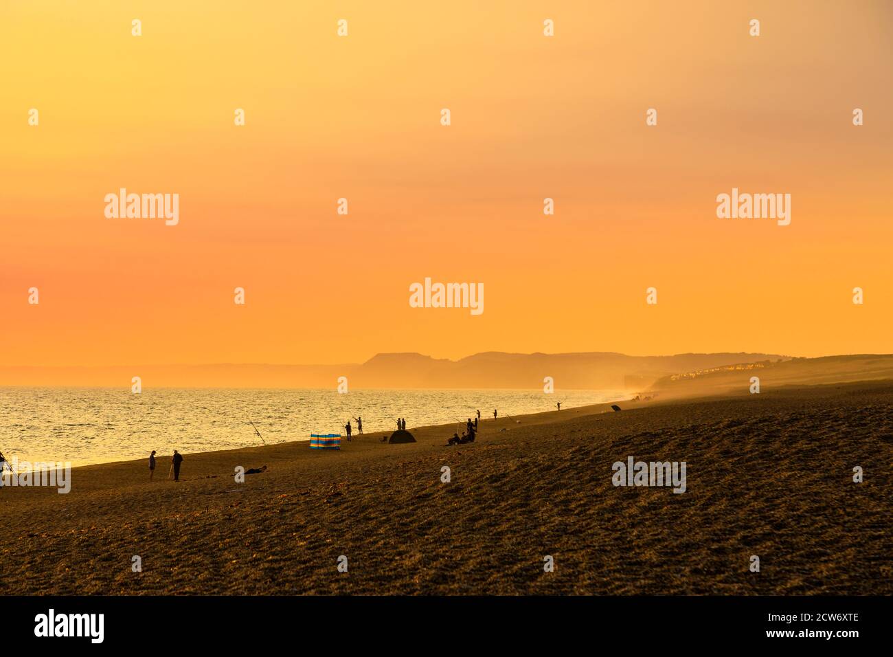 Fishermen on the beach at sunset at West Bexington, a village in south-west Dorset, England, sited behind Chesil Beach near Bridport Stock Photo