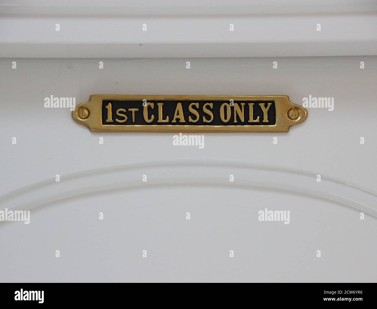 A first class only brass sign on a white door. Stock Photo