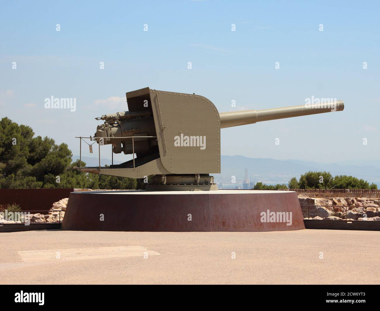 Old military cannon at Montjuïc Castle in Barcelona Spain pointing to the right. Clear blue sky with city in the background. Stock Photo
