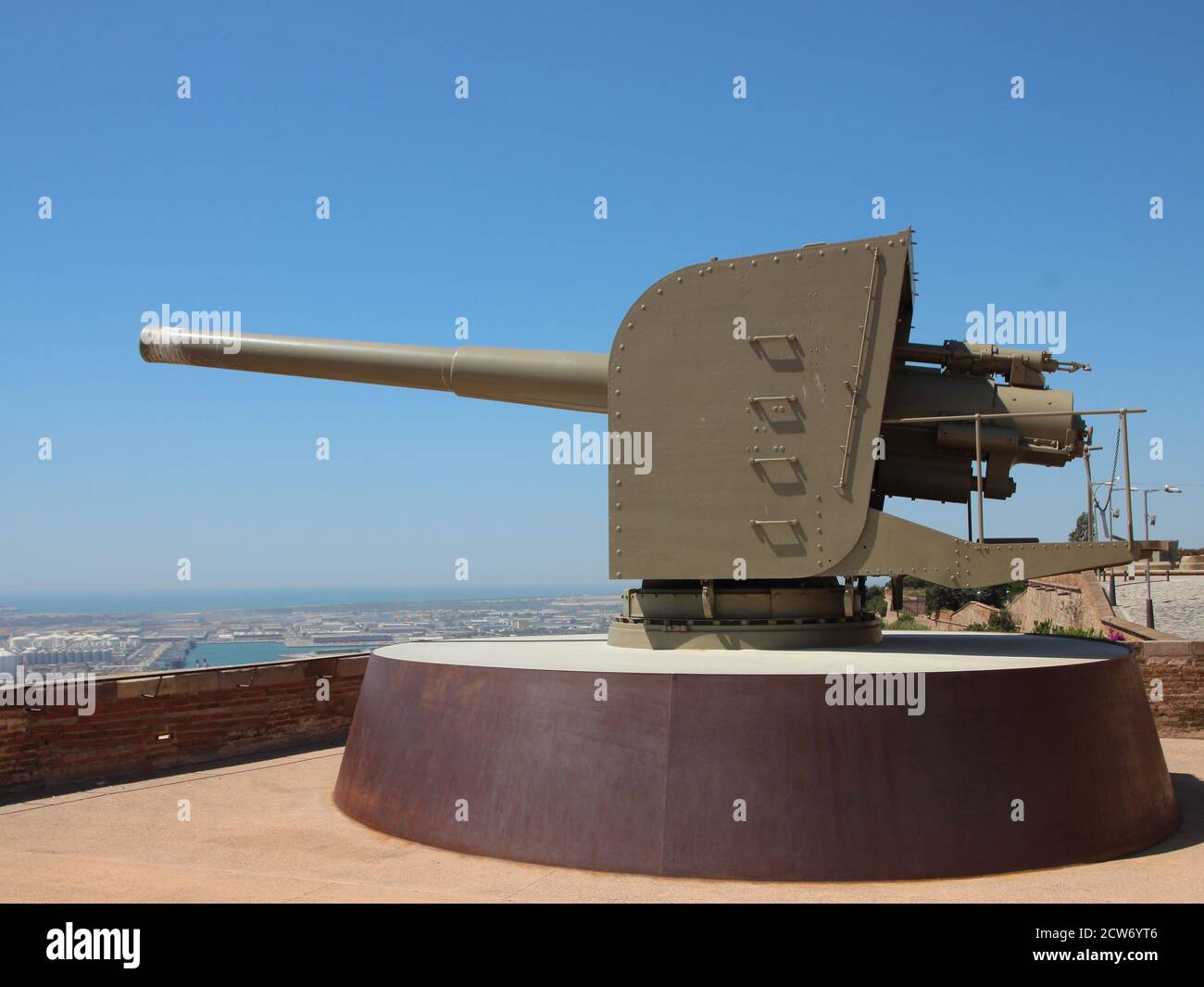 Old military cannon at Montjuïc Castle in Barcelona Spain pointing to the left. Clear blue sky with city in the background. Stock Photo