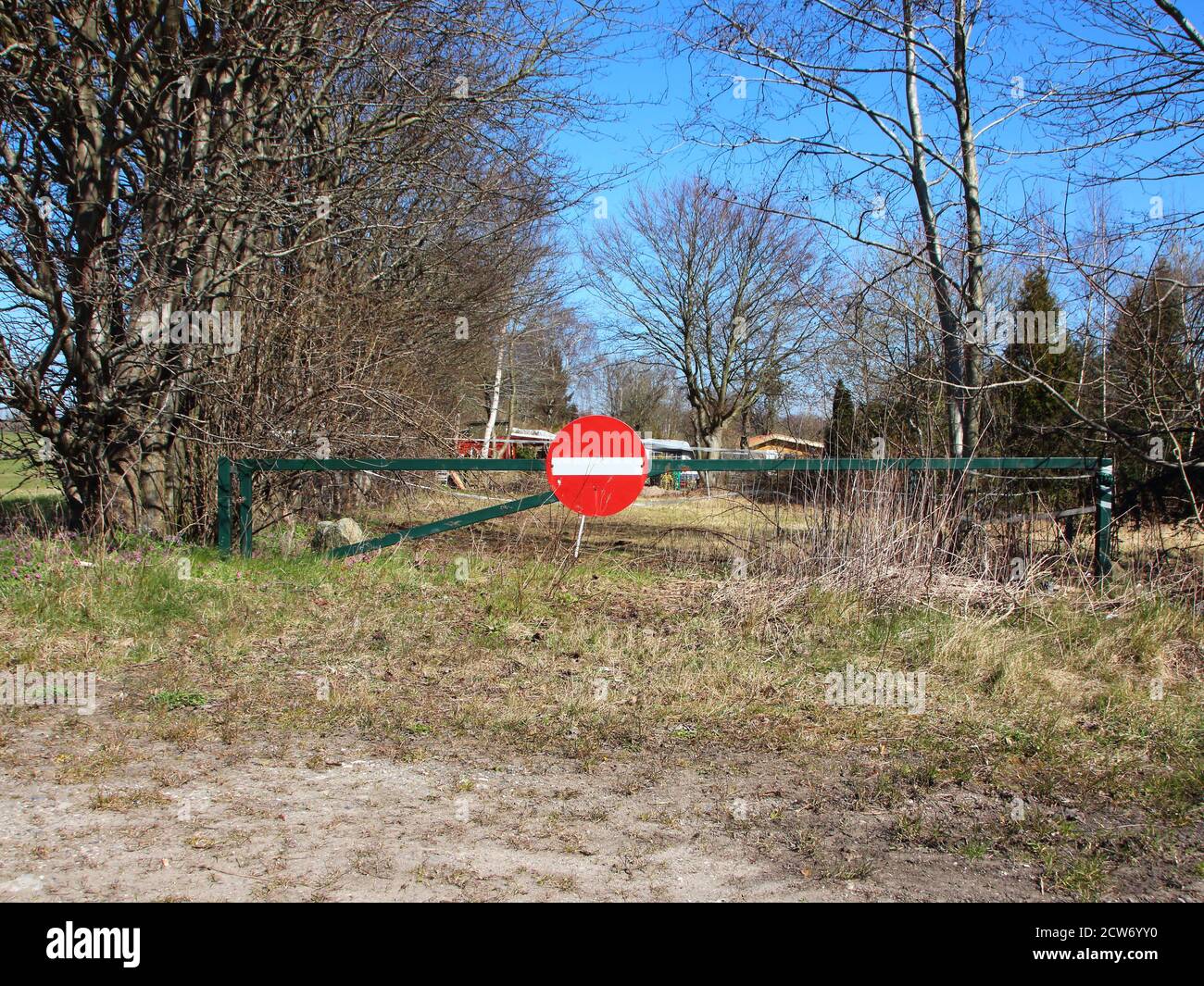 A red and white stop sign on a green barrier at a field entrance. Stock Photo