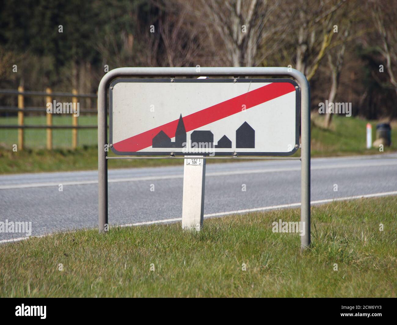 A traffic sign signifying leaving town. Trees are in the background and the sign stands on grass. Stock Photo