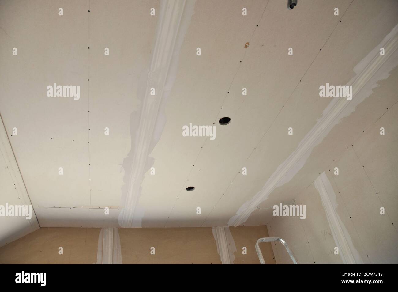 Closeup on plastering, skim coating, finishing a drywall ceiling and