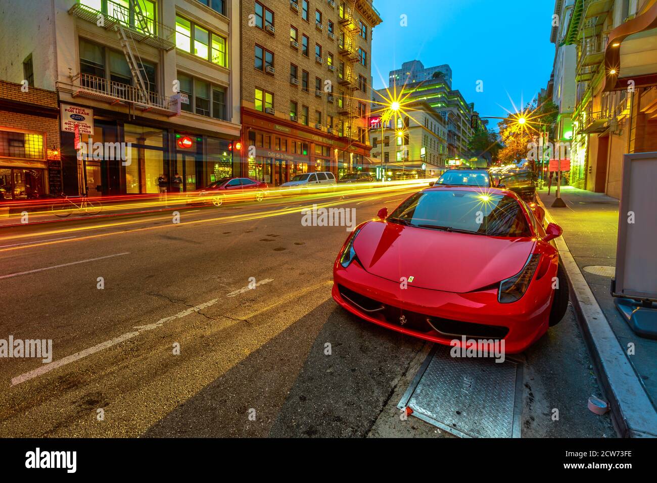 San Francisco, California, United States - August 16, 2019: Ferrari car parked on the street of San Francisco downtown by night. Light trails of cars Stock Photo