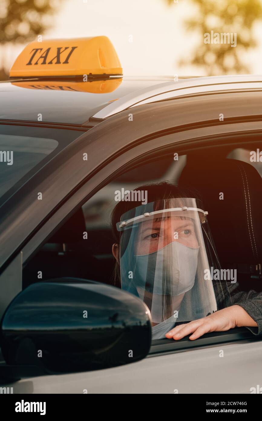 Female taxi driver with protective face mask and plastic visor waiting