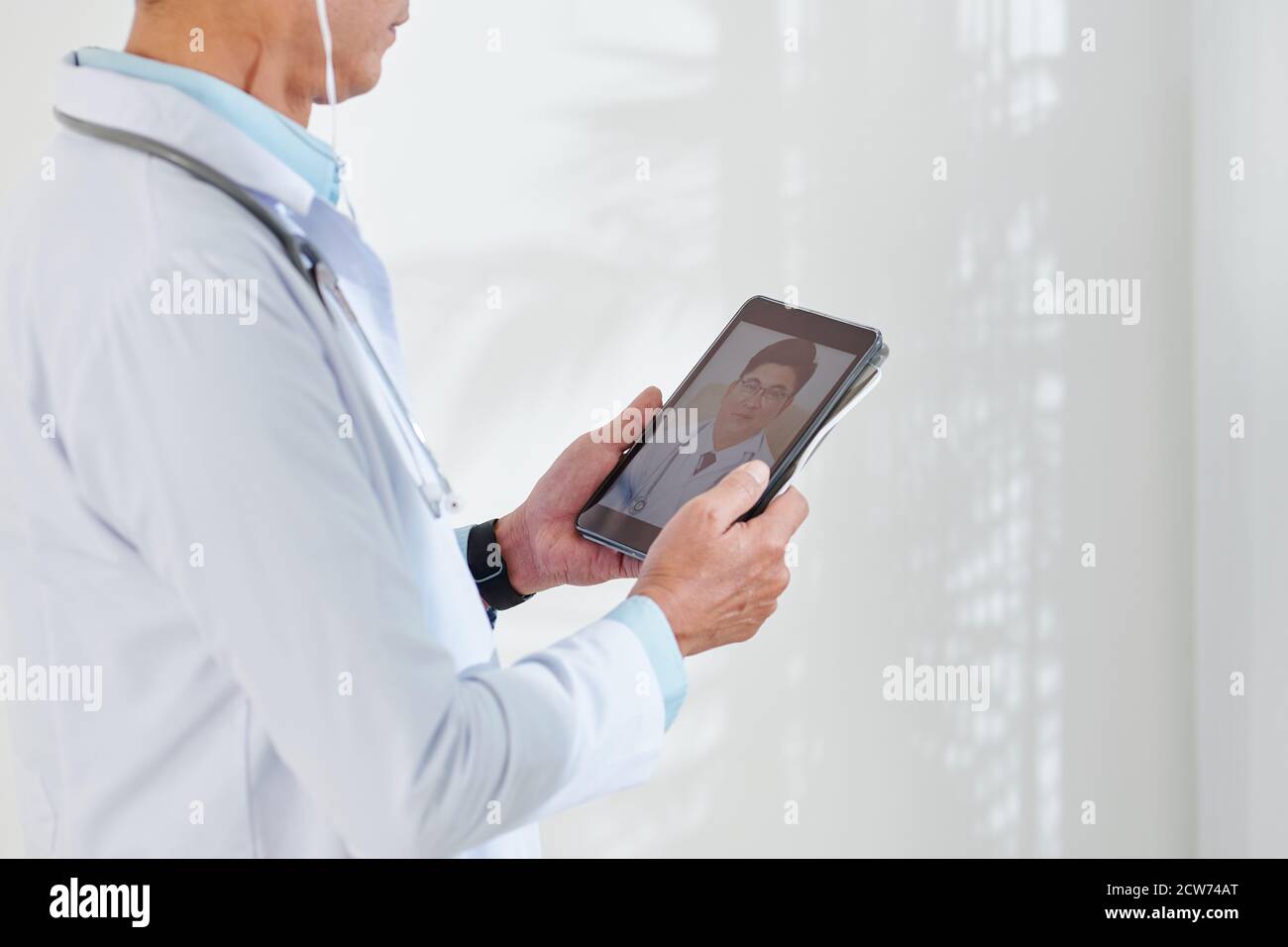 Physician video calling colleague Stock Photo