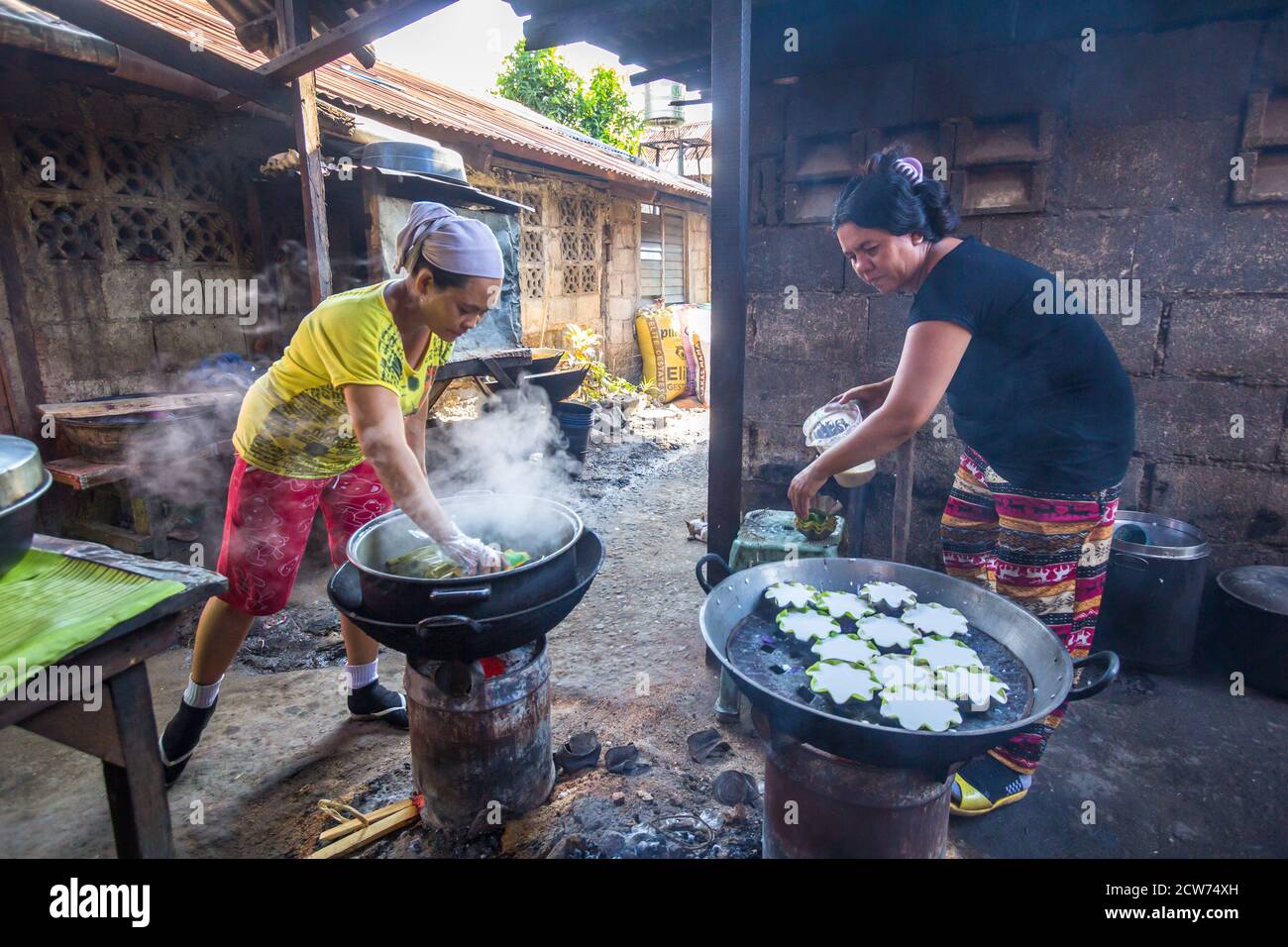 Two Filipino women preparing traditional rice cakes Stock Photo