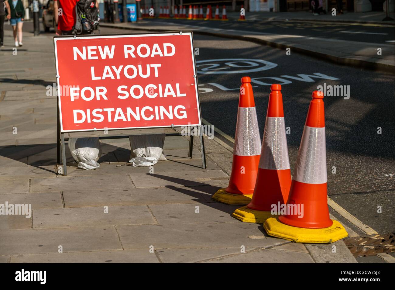 LONDON - SEPTEMBER 13, 2020: A UK road sign with orange traffic cones telling users that the layout has changed to allow for social distancing during Stock Photo