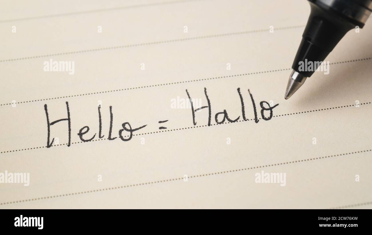 Beginner German or Dutch language learner writing Hello word Hallo for homework on a notebook macro shot Stock Photo