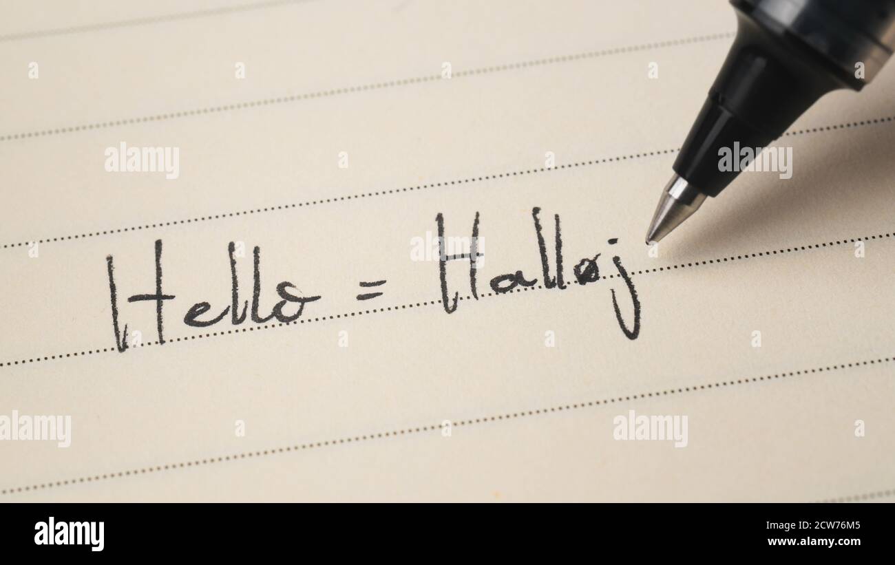 Beginner Danish language learner writing Hello word Halloj for homework on a notebook macro shot Stock Photo