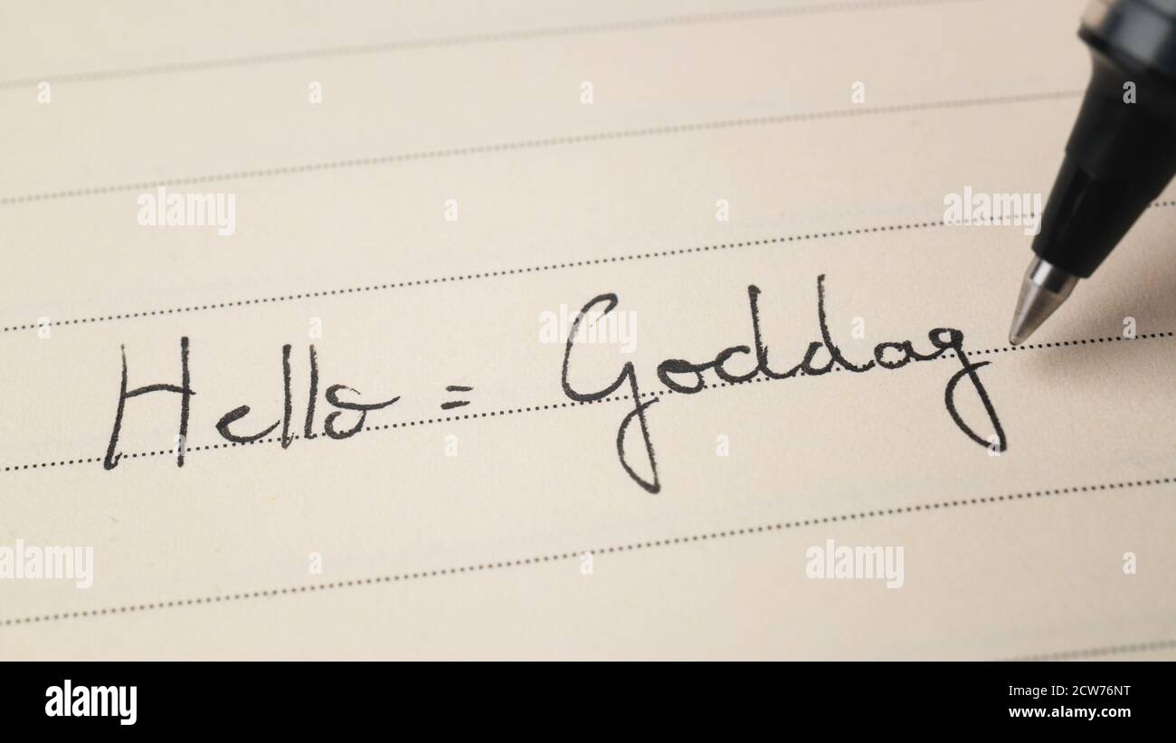Beginner Danish language learner writing Hello formal word Goddag for homework on a notebook macro shot Stock Photo