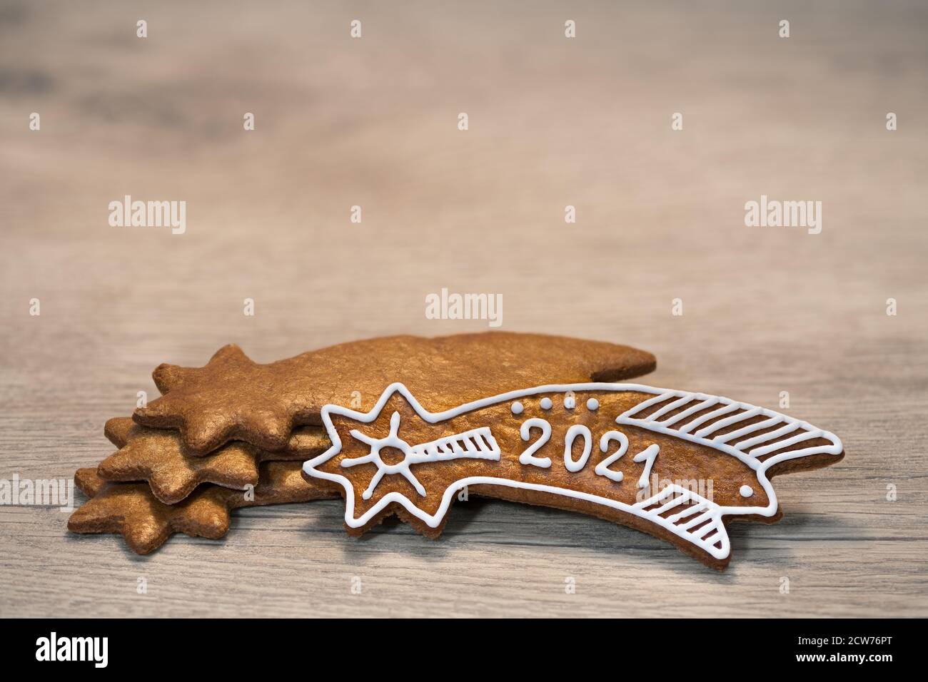 New Year 2021 on ornate gingerbread Bethlehem star for good luck laid on wood background. Gold baked sweet Christmas cookie decorated with white icing. Stock Photo
