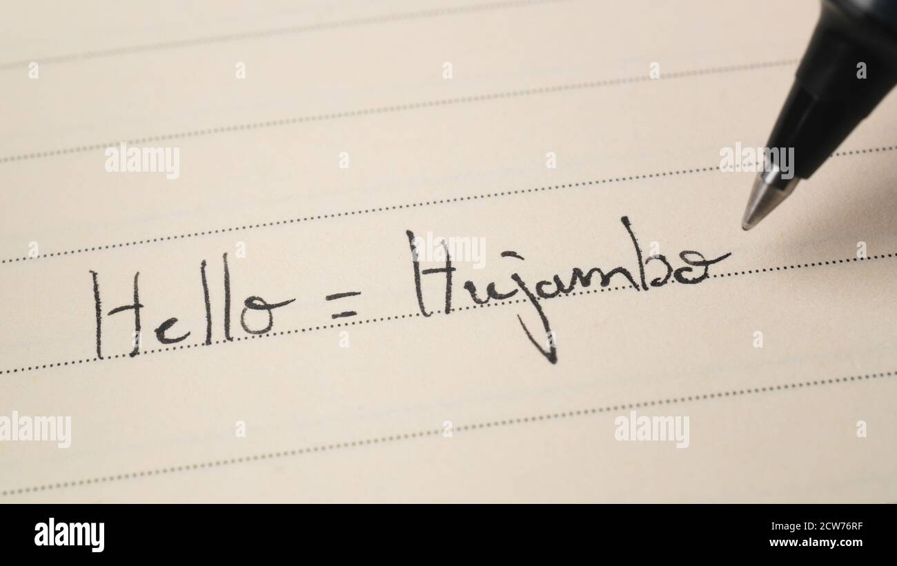 Beginner Swahili language learner writing Hello word Hujambo for homework on a notebook macro shot Stock Photo