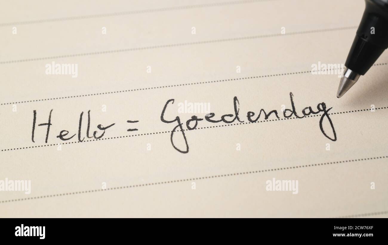 Beginner Dutch language learner writing Hello formal word Goedendag for homework on a notebook macro shot Stock Photo
