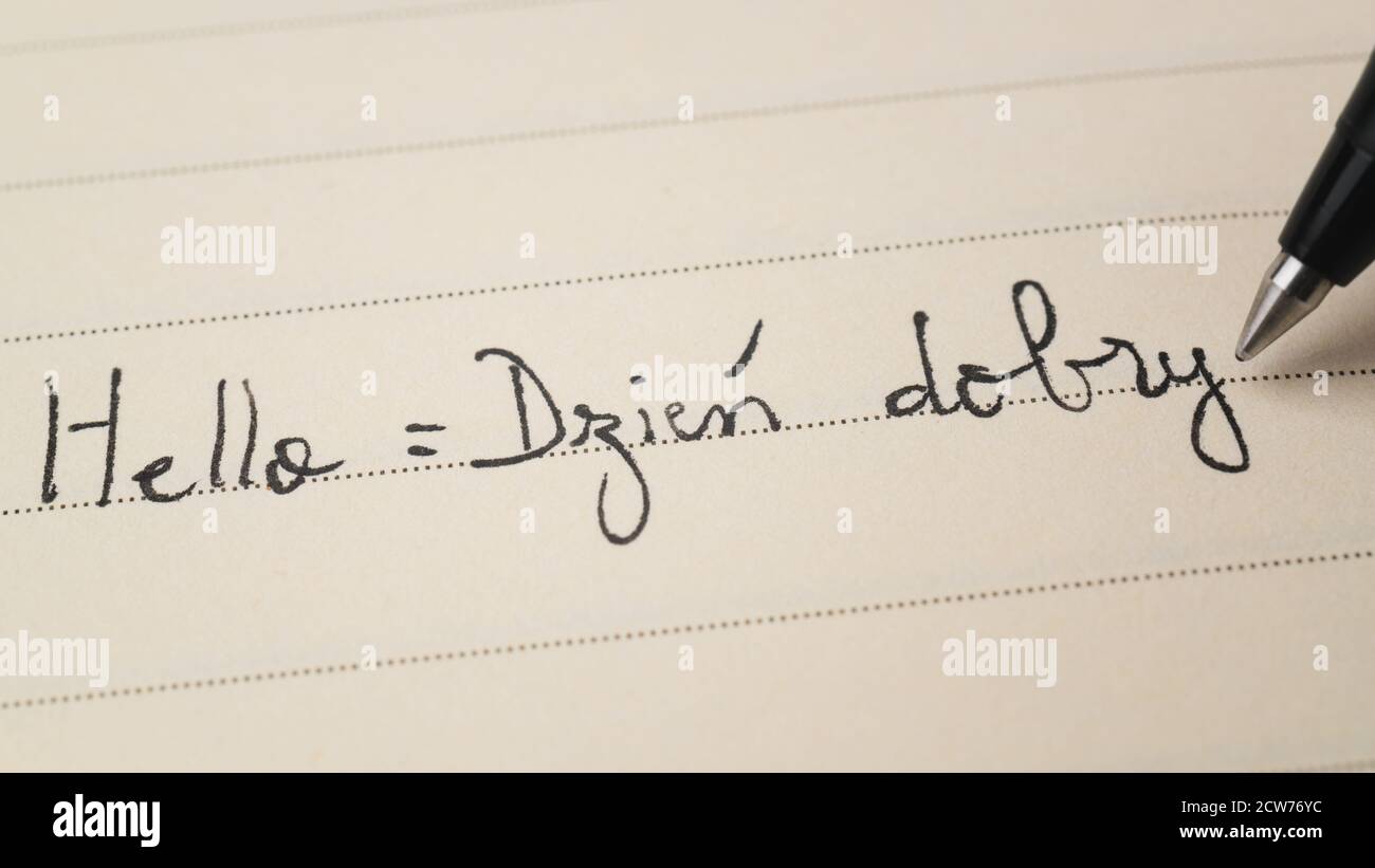 Beginner Polish language learner writing Hello formal word Dzien dobry for homework on a notebook macro shot Stock Photo