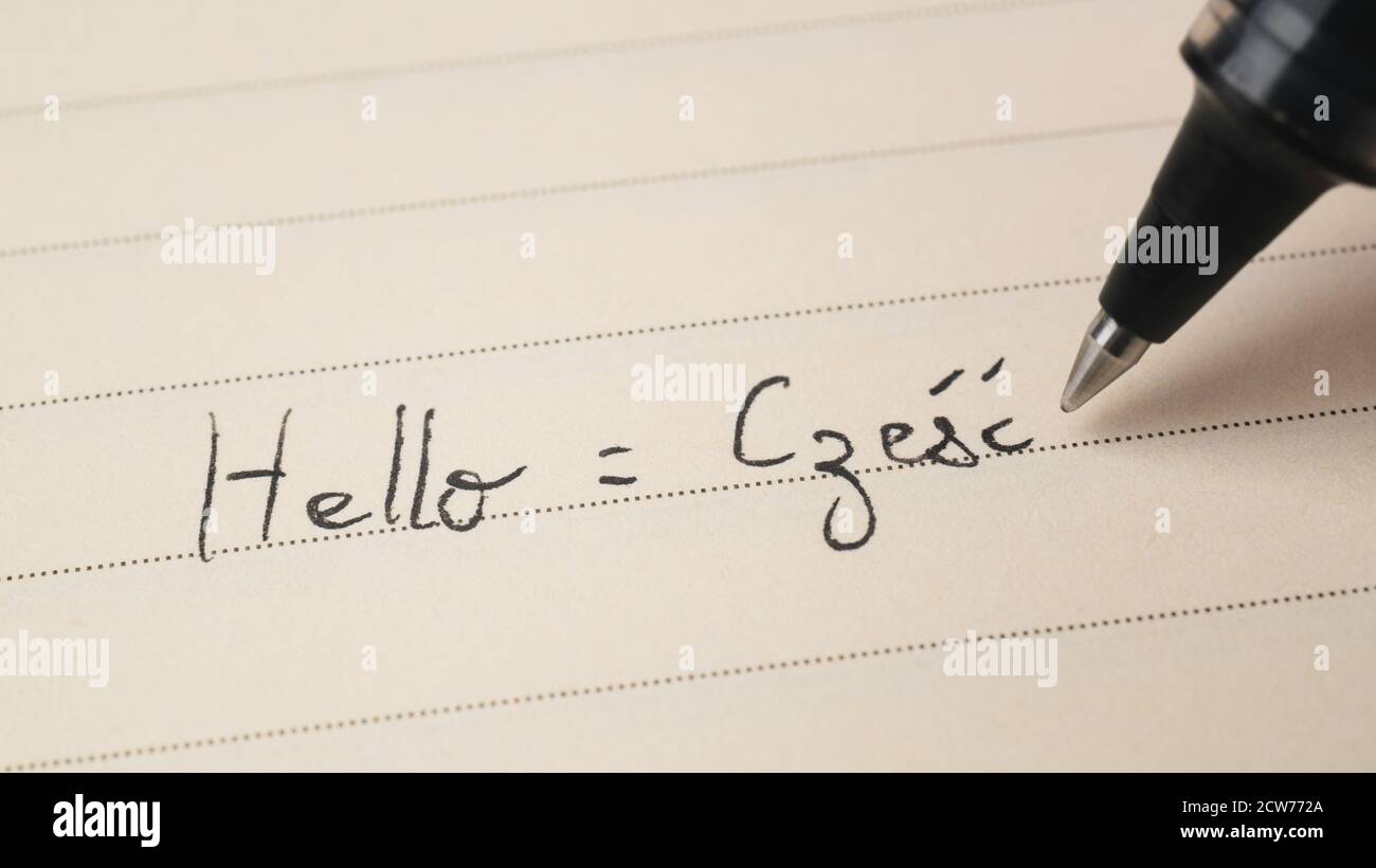 Beginner Polish language learner writing Hello word Czesc for homework on a notebook macro shot Stock Photo