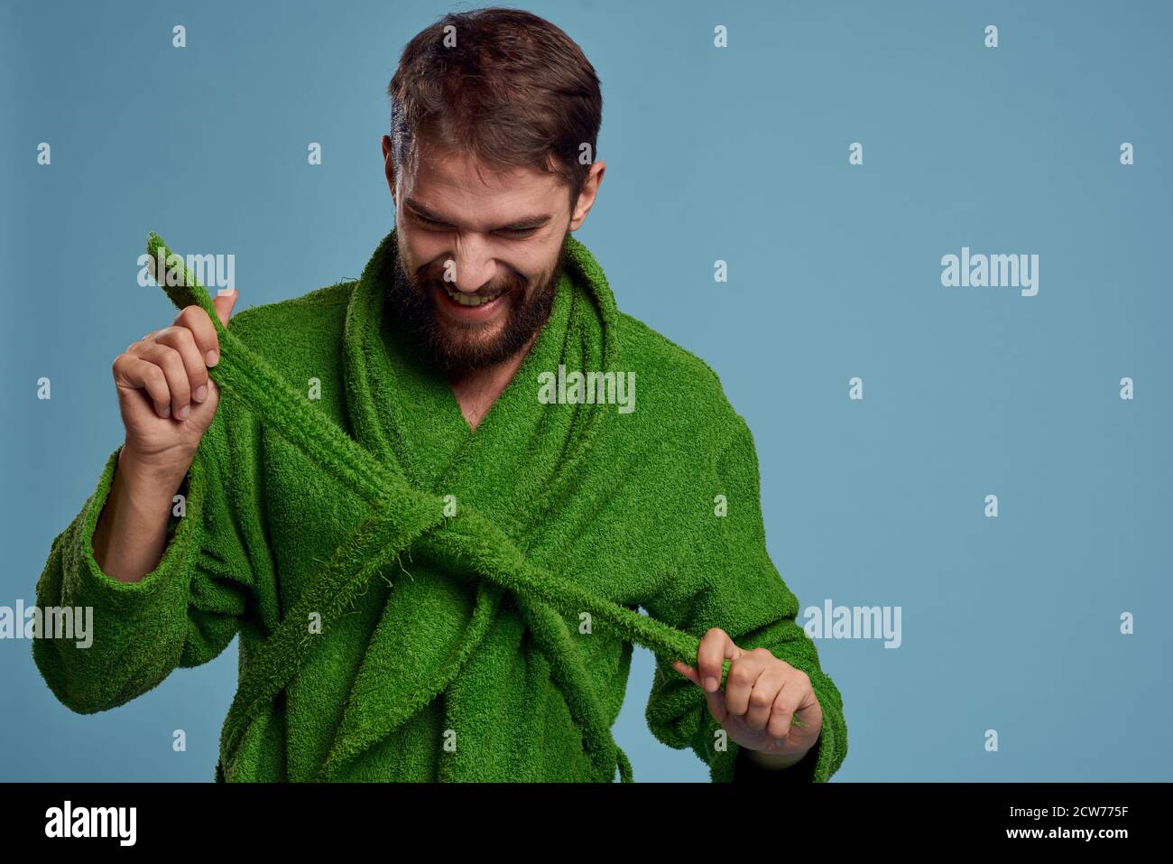 Bearded man in green robe with belt on blue background cropped view of ...
