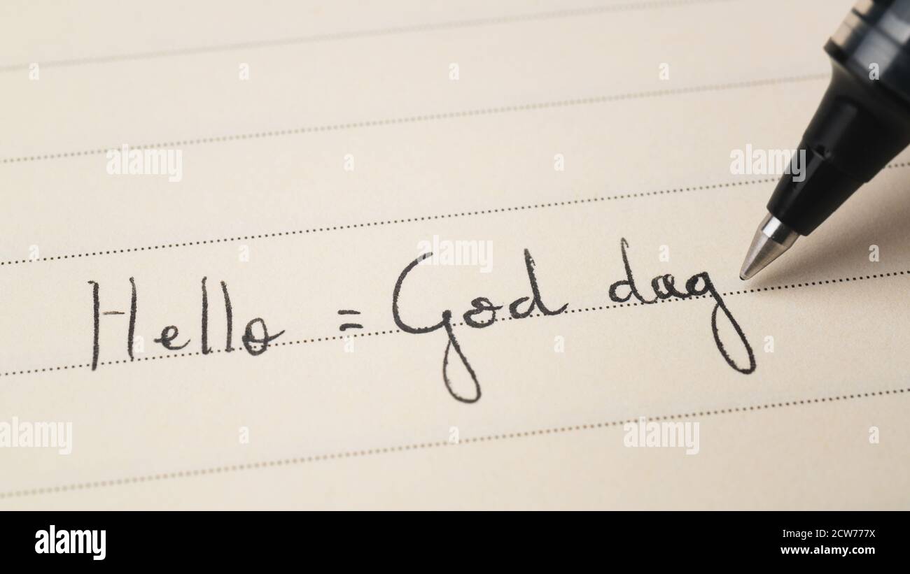 Beginner Swedish or Norwegian language learner writing Hello formal word God dag for homework on a notebook macro shot Stock Photo