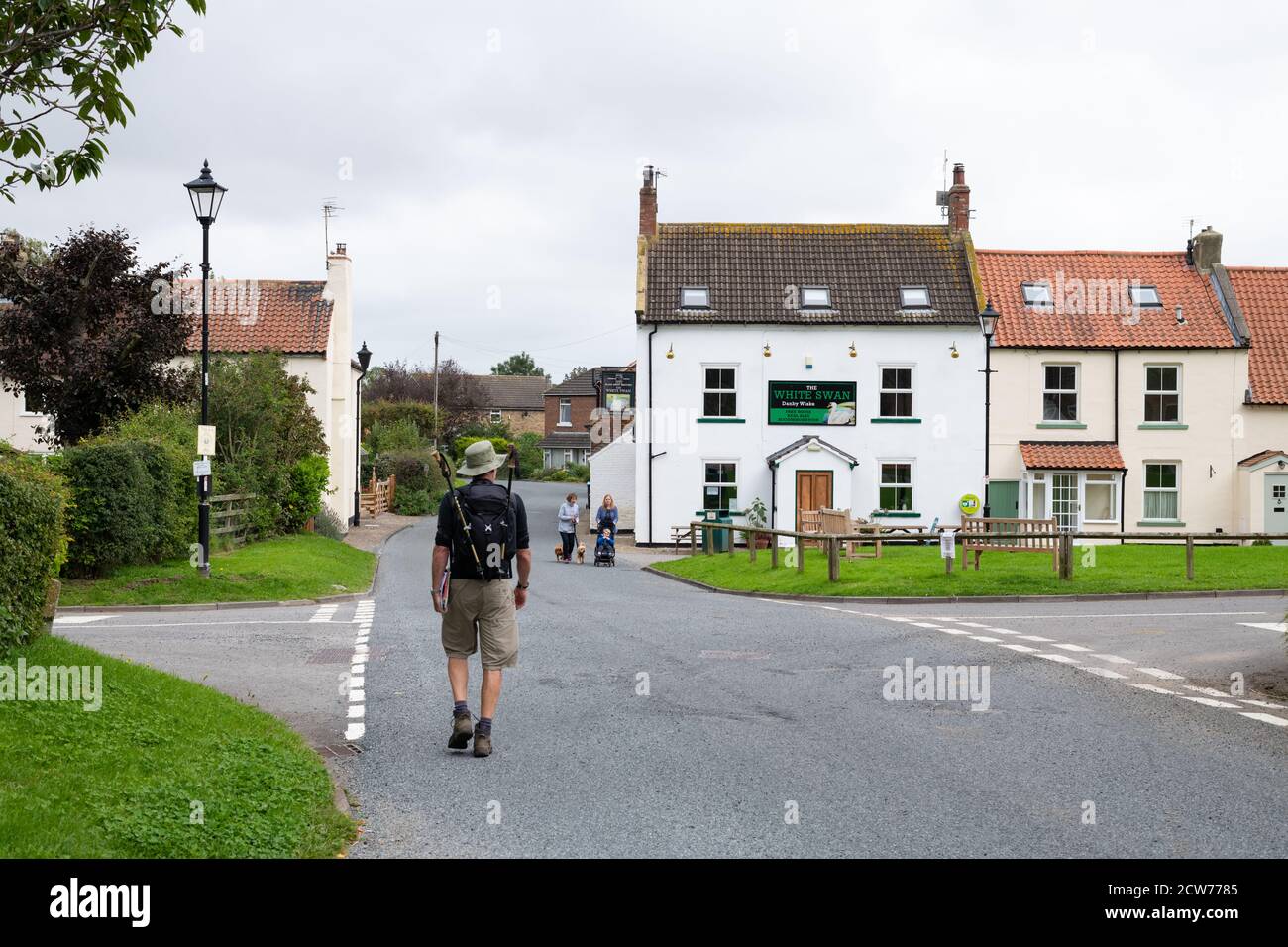 walker approaching The White Swan village inn pub, Danby Wiske, North Yorkshire, England, UK - lies directly on Wainwright's Coast to Coast walk Stock Photo