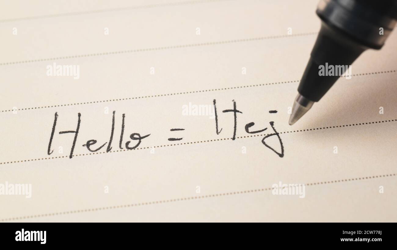Beginner Swedish language learner writing Hello word Hej for homework on a notebook macro shot Stock Photo
