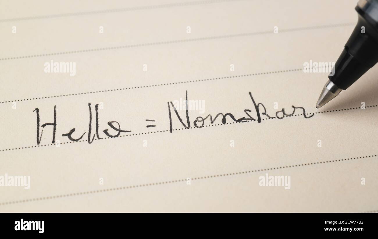 Beginner Bengali Bangla language learner writing Hello word Nomskar for homework on a notebook macro shot Stock Photo