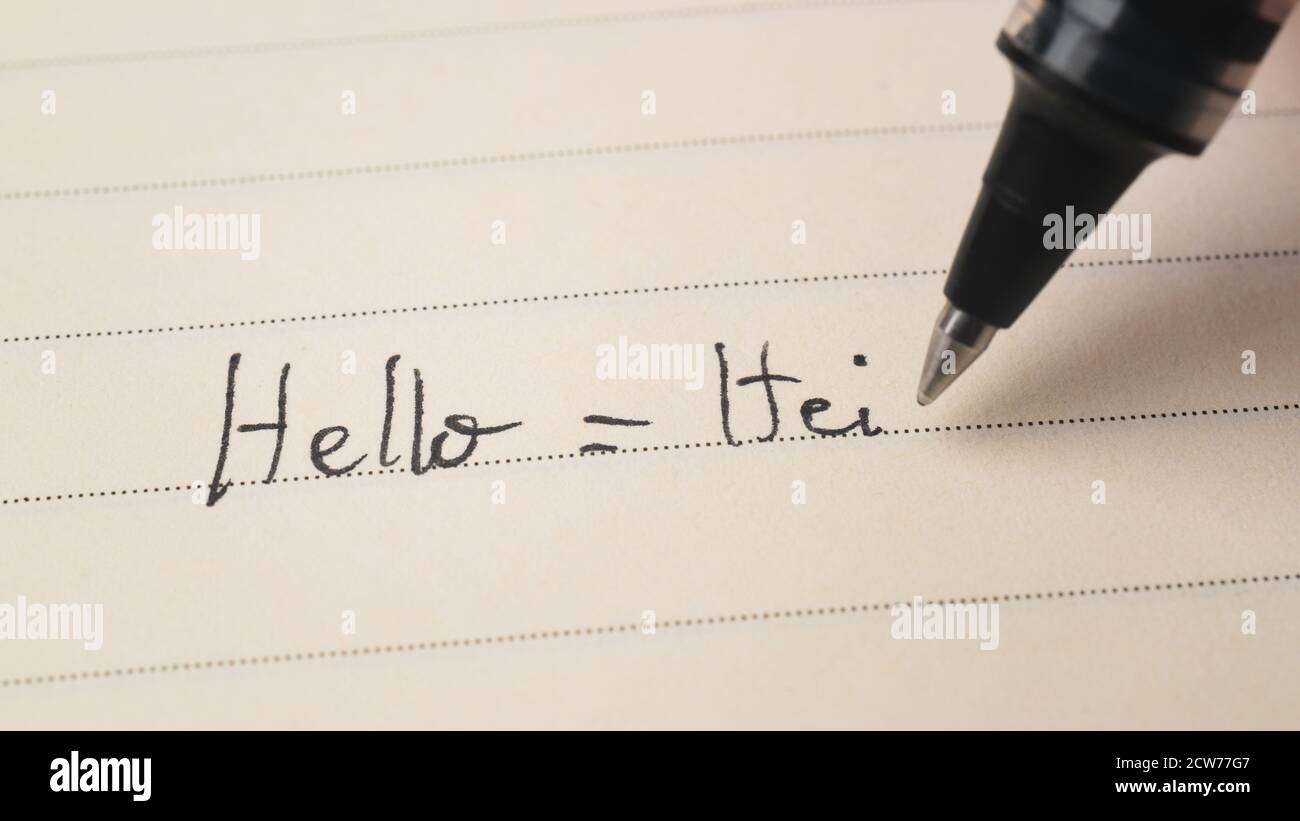 Beginner Finnish or Norwegian language learner writing Hello word Hei for homework on a notebook macro shot Stock Photo