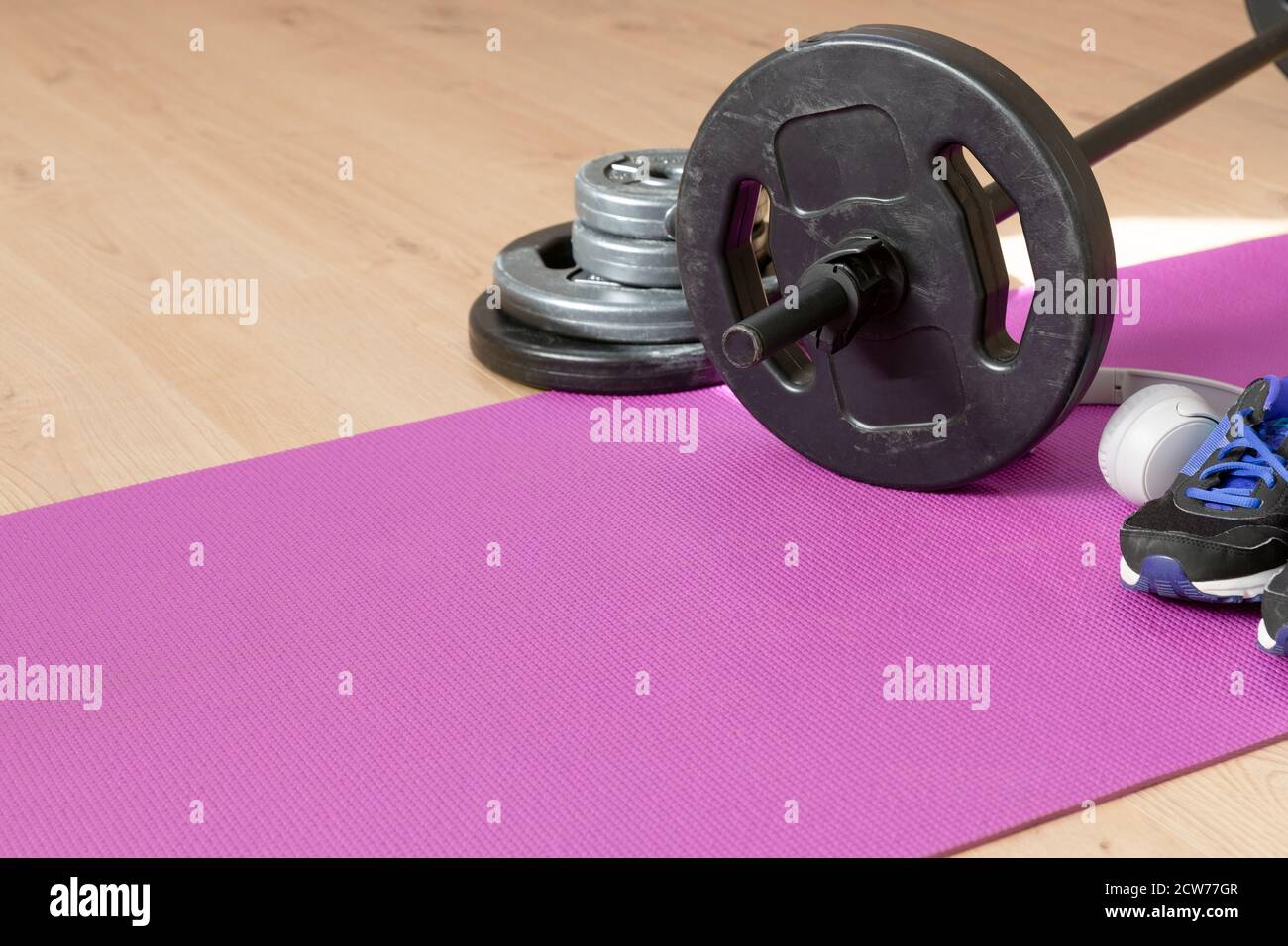 Fitness tools dumbbells yoga mat and shoes on a wooden floor in natural light. Healthy living concept. Stock Photo