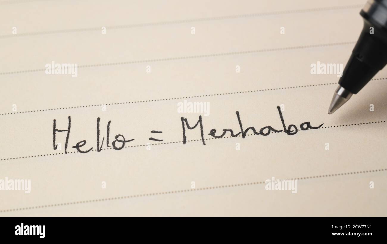 Beginner Turkish language learner writing Hello word Merhaba for homework on a notebook macro shot Stock Photo