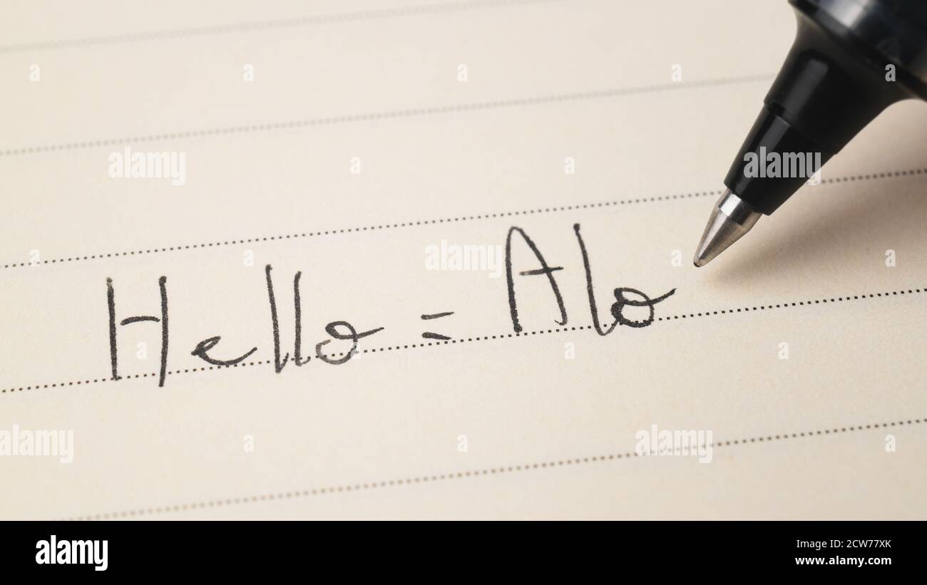 Beginner Romanian language learner writing Hello informal word Alo for homework on a notebook macro shot Stock Photo