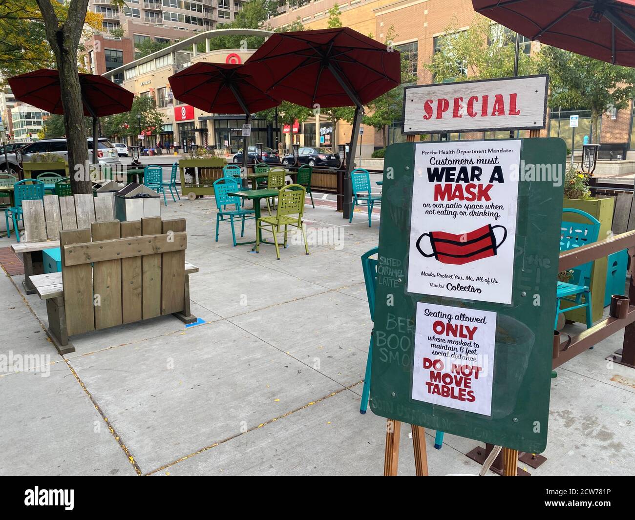 Outdoor seating area at Colectivo Coffee in Evanston, IL. Signs at the entrance remind customers to social distance and wear masks. Stock Photo