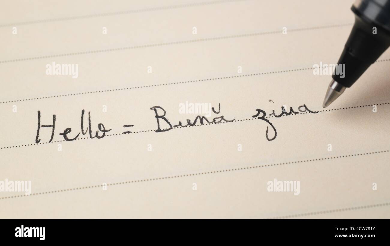 Beginner Romanian language learner writing Hello word Buna ziua for homework on a notebook macro shot Stock Photo