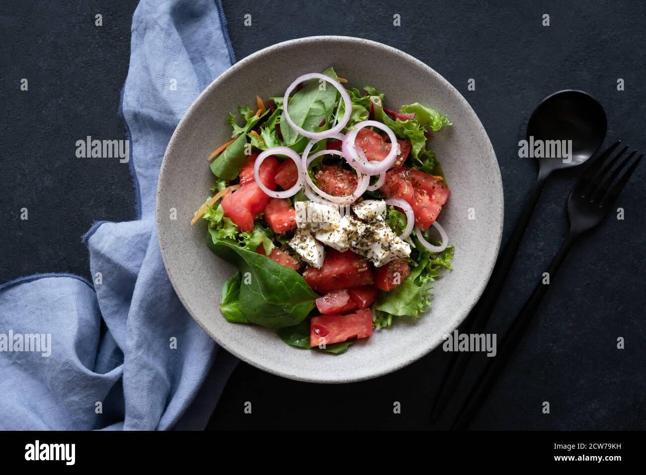 Greek salad in bowl on black background, table top view. Healthy vegetable salad with feta cheese Stock Photo
