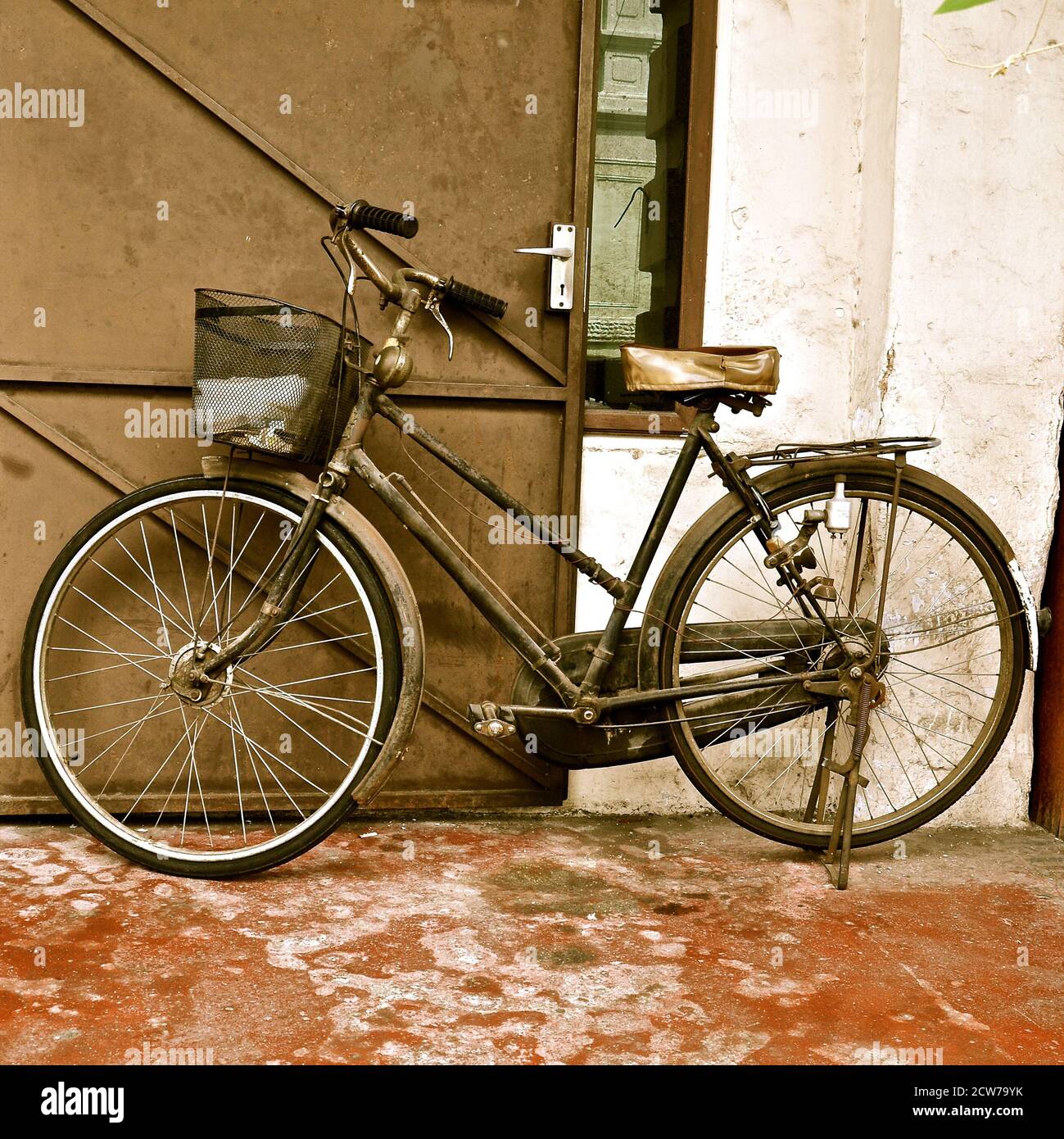 Vintage bicycle parked against a wooden door. Stock Photo