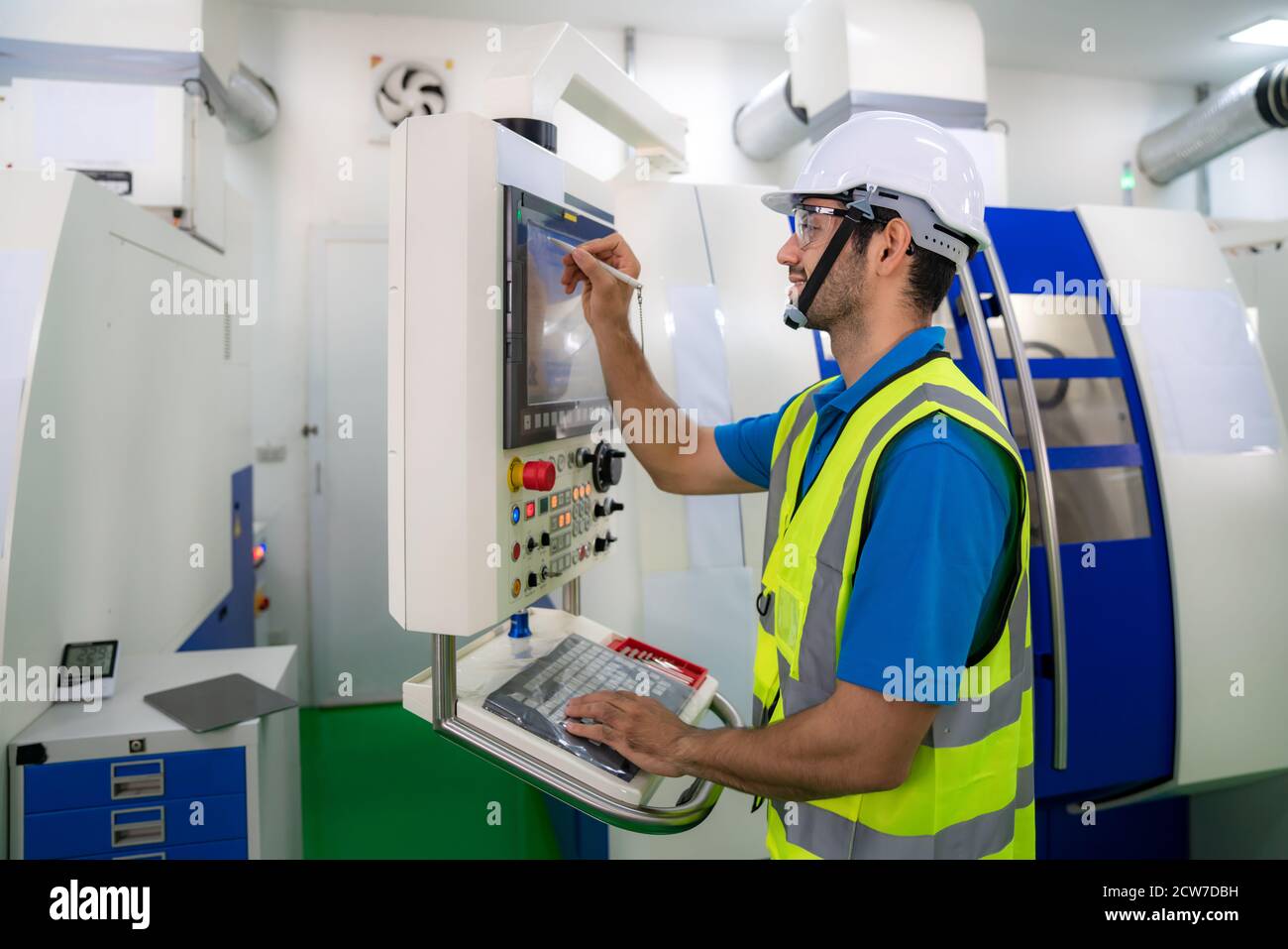 Mechanical technician operative entering data in cnc milling cutting machine at factory at tool workshop in metal machining industry. Stock Photo