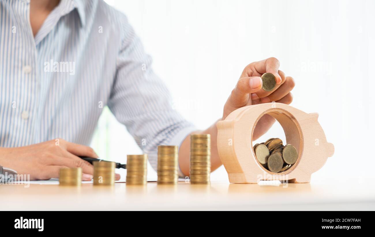 woman hand putting money coin into piggy bank with step of growing ...