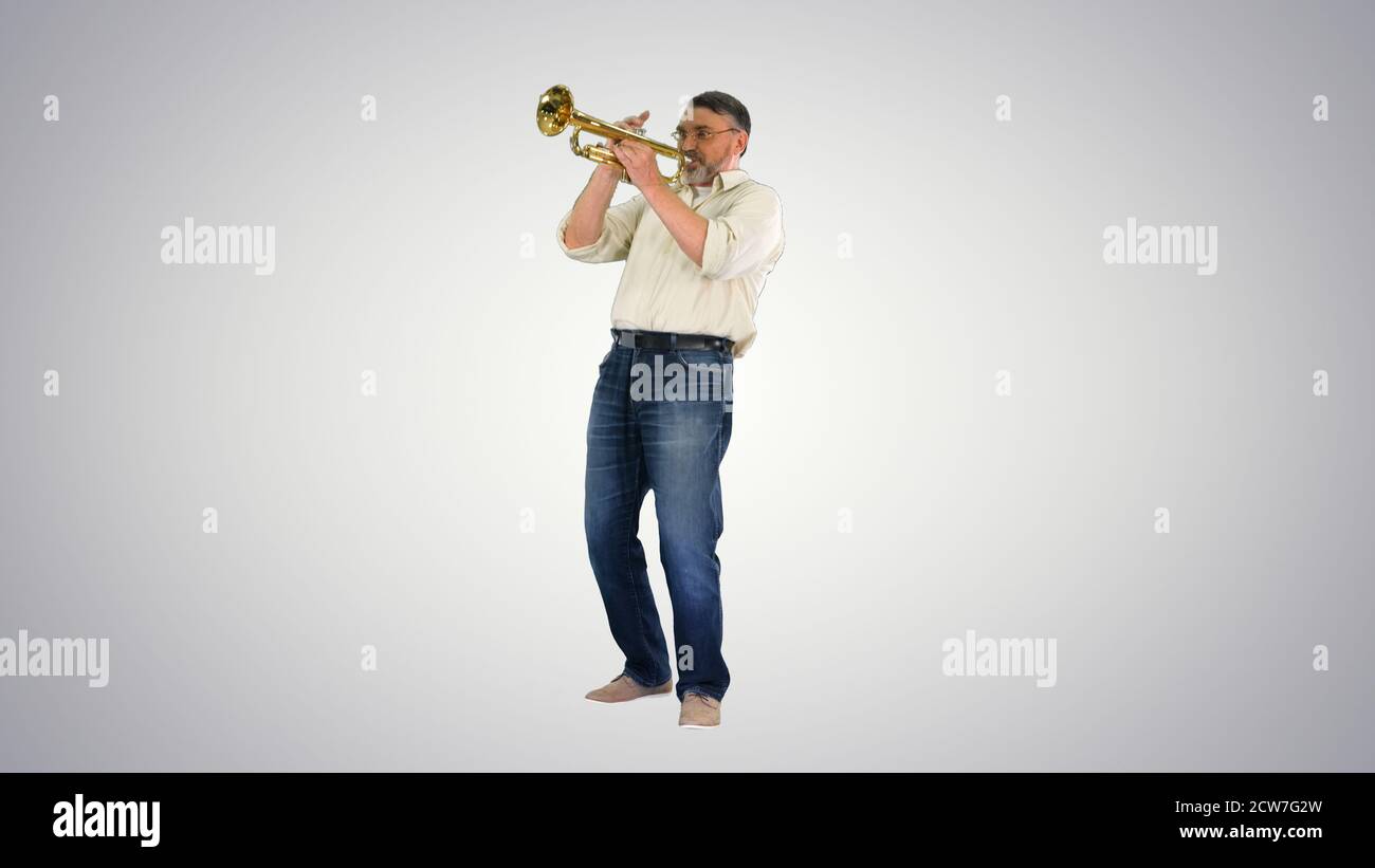 Senior musician playing a trumpet on gradient background. Stock Photo