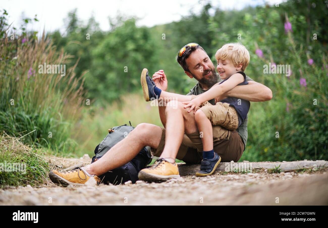 Father with small son hiking outdoors in summer nature, resting. Stock Photo