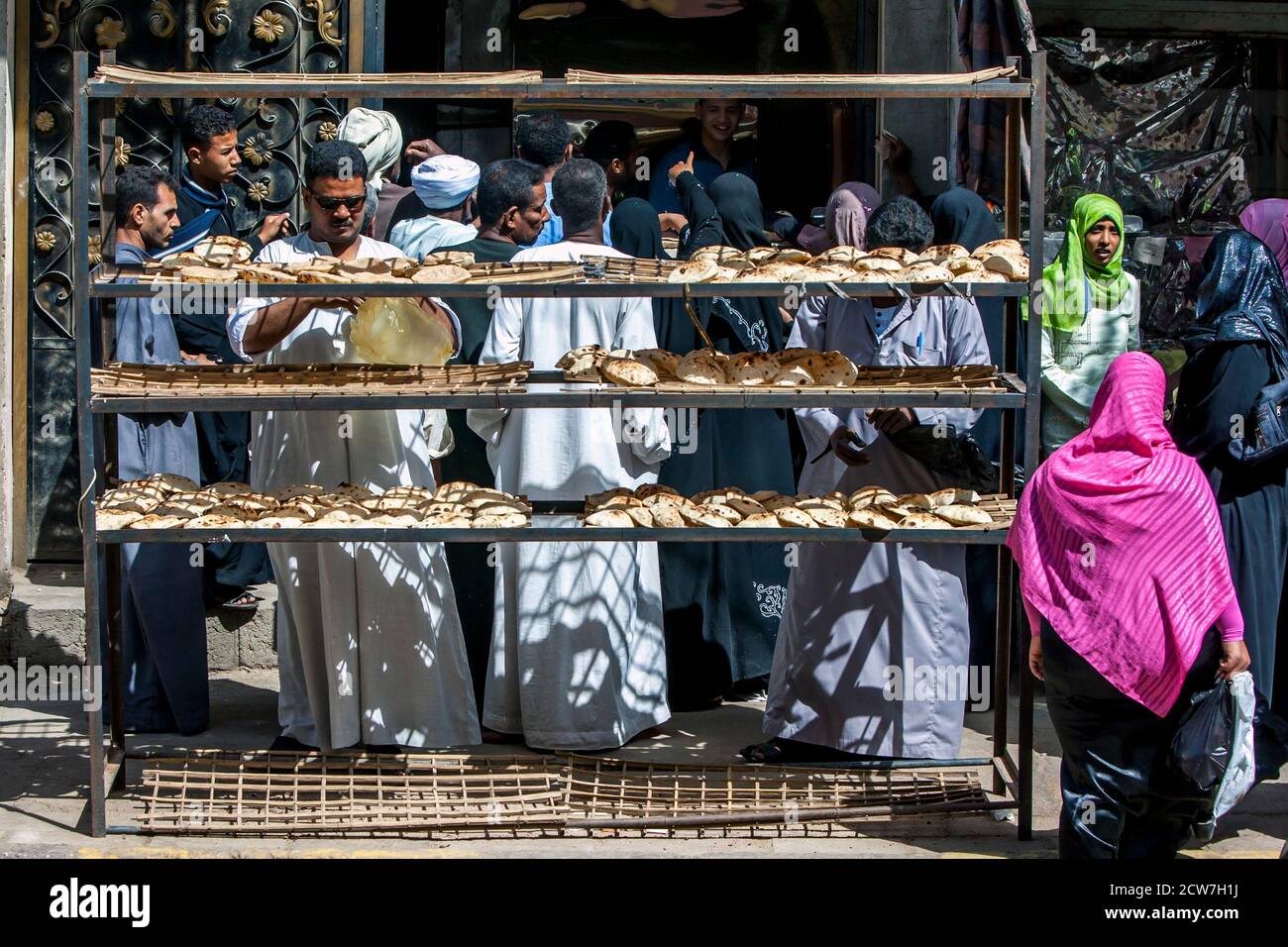 EDFU, EGYPT - MARCH 17, 2010 : Customers crowd around the entrance to a bakery in Edfu in Egypt. Bread forms the basis for all Egyptian meals. Stock Photo