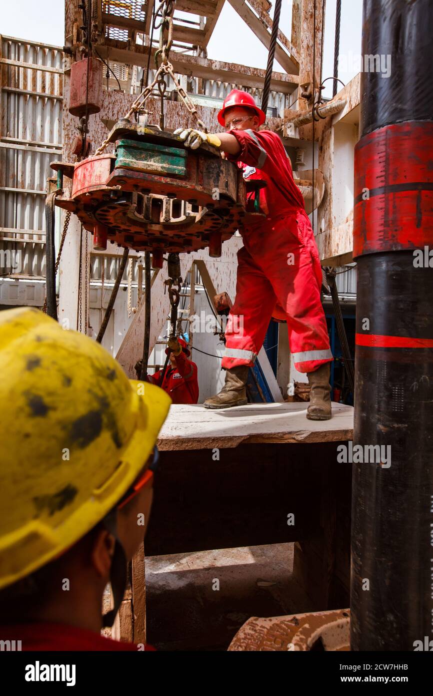 Oil deposit. Worker using electric clincher for connecting drilling pipes. Zhaik-Munai oil deposit, Kazakhstan. Stock Photo