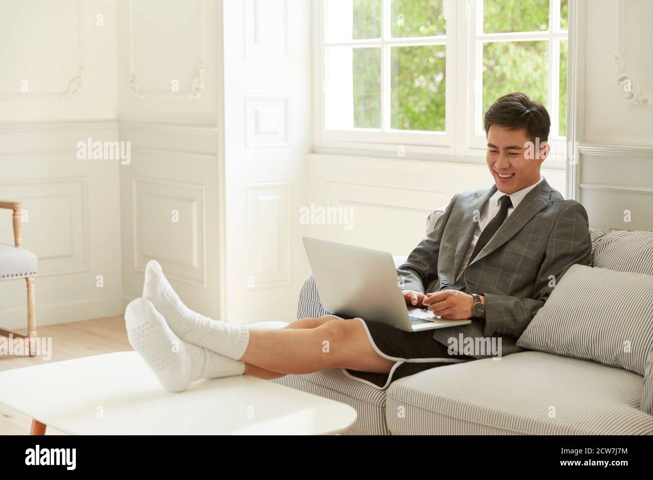 young asian business man wearing suit and shorts working from home meeting with colleagues online using video chat on laptop computer Stock Photo