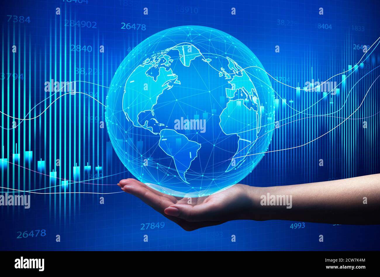 Hand Holding Globe Over Blue Background With Global Economy Graphs Stock Photo