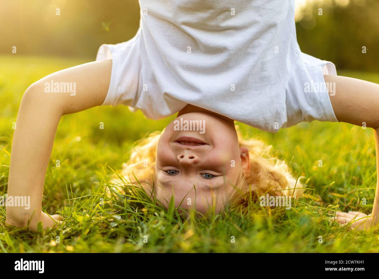 Little boy standing upside down in park Stock Photo - Alamy