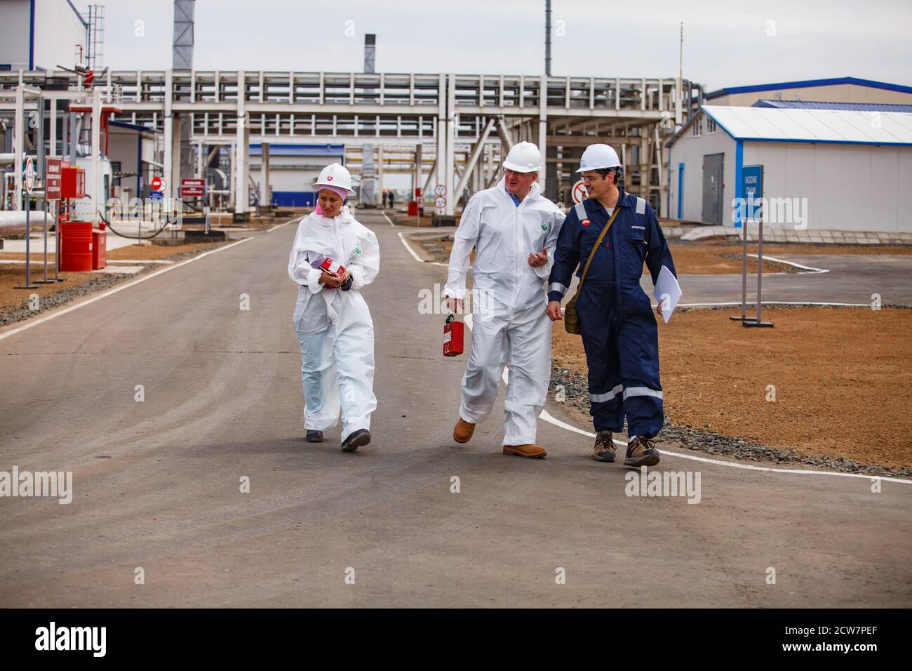 Oil refinery and gas processing plant. Three specialists oil engineers on pipelines background. Zhaik-Munai oil deposit, Kazakhstan. Stock Photo