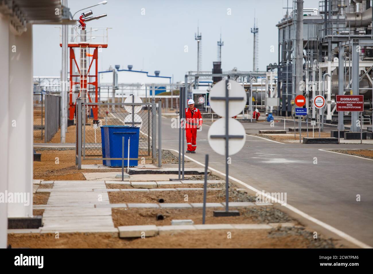 Oil refinery and gas processing plant in desert. Engineer in red overalls and white helmet. Zhaik-Munai oil deposit, Kazakhstan. Stock Photo